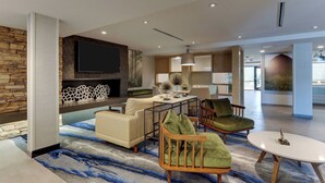 A modern living room with a fireplace, a flat-screen TV, and a dining area with a table and chairs.