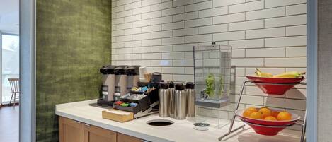 A kitchen counter with a coffee machine, thermos bottles, and fruit bowls.