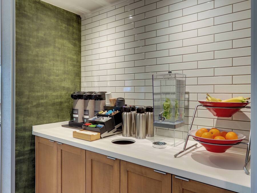 Un piano di lavoro in cucina con una macchina da caffè, thermos e ciotole di frutta.