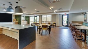 A modern restaurant with a central island, wooden tables, and pendant lighting.