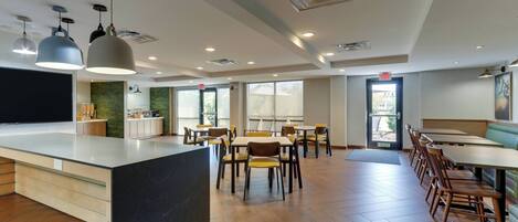 Un restaurante moderno con una isla central, mesas de madera e iluminación colgante.