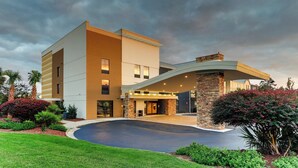 A modern hotel with a curved entrance, a stone facade, and a landscaped driveway.