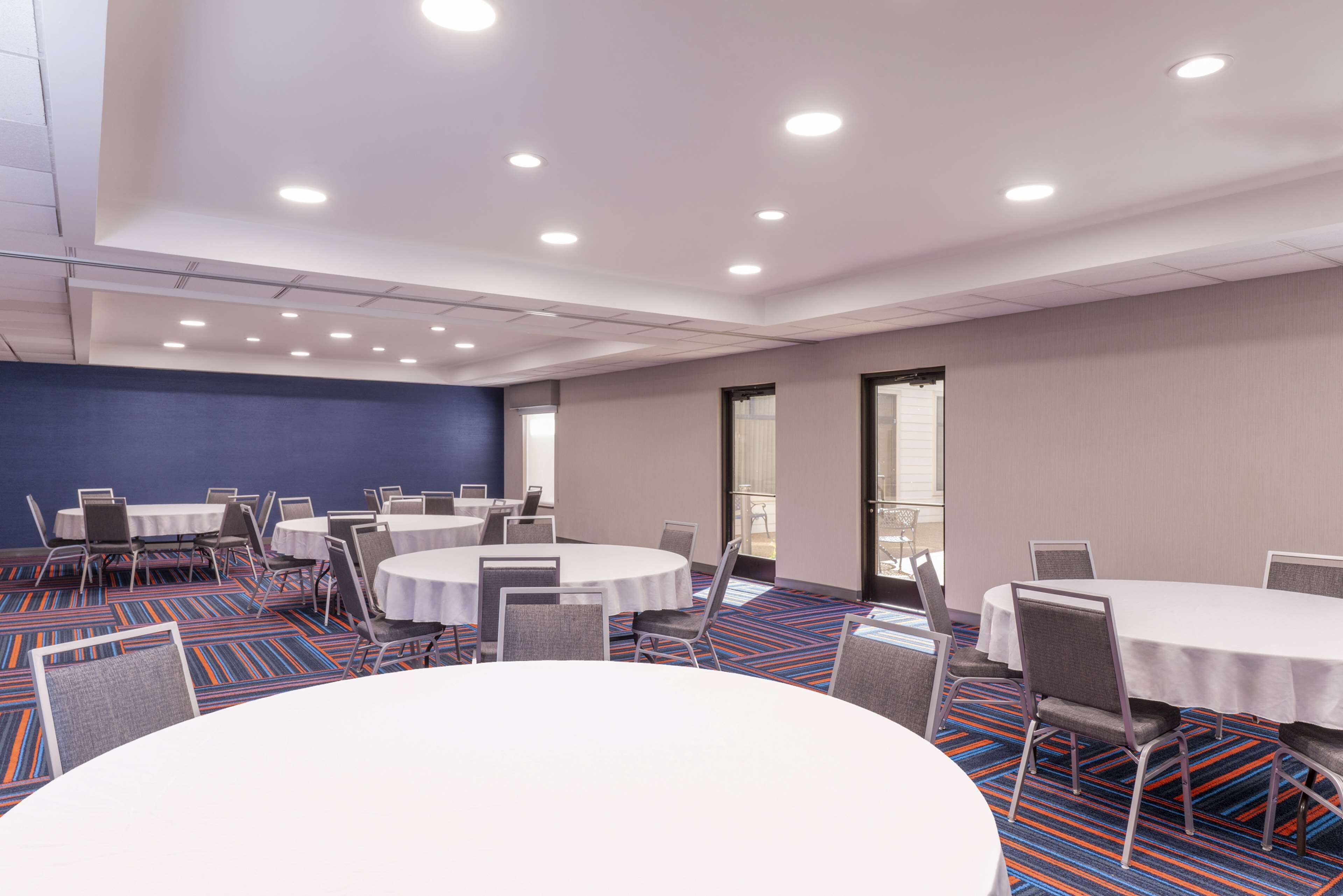 A conference room with round tables and chairs, a patterned carpet, and a blue accent wall.
