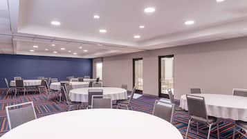 A conference room with round tables and chairs, a patterned carpet, and a blue accent wall.