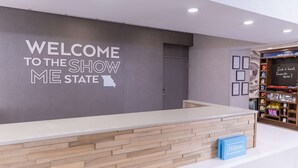 Ein Empfangstisch mit einem Schild, auf dem 'WELCOME TO THE SHOW ME STATE' steht, einer Holztresen und einem Hilton Honors Schild.