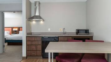 Ein kleines Hotelzimmer mit Küchenzeile, einem Bett und einem Essbereich.