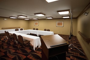 A conference room with a long table, chairs, a podium, and framed pictures on the walls.