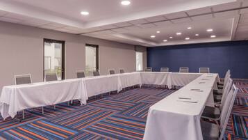 Un salón de conferencias con una larga mesa, sillas y piso alfombrado.