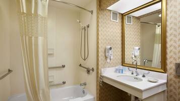 A bathroom with a bathtub, shower, and sink with a mirror.