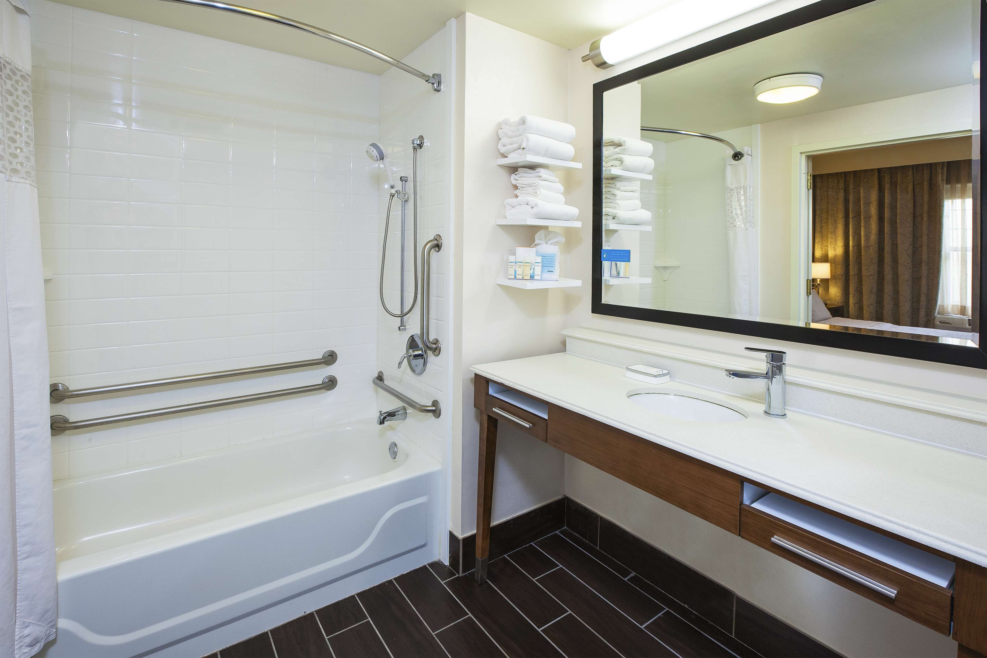 Un baño moderno con bañera, tocador con espejo y barra para toallas.