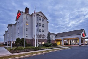 Un hotel con una destacada bandera estadounidense, una entrada despejada y un césped bien cuidado.