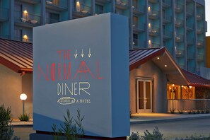 A sign for "The Normal Diner" at a hotel, with a modern building in the background.