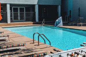 A swimming pool with lounge chairs and a covered area.