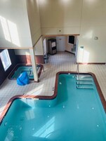 Una piscina interior con varias pistas de natación, un vestuario y un pequeño ventanal.