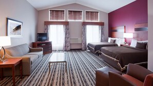 Een hotelkamer met een bank, twee bedden, een televisie, een bureau en een kamerbreed tapijt met dessin.