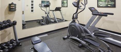 A gym with exercise equipment including treadmills, an elliptical, and dumbbells.