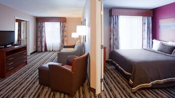 Habitación de hotel con cama, televisión, escritorio, silla y piso alfombrado.