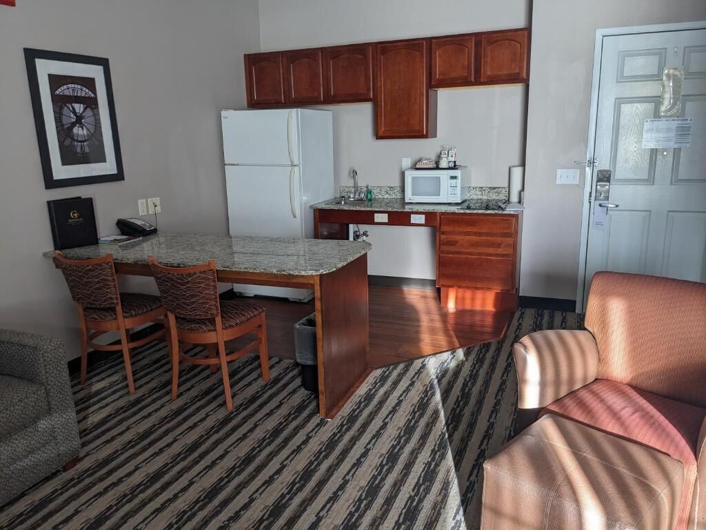 Un espacio habitable compacto con comedor, kitchenette y una puerta que da a otra habitación.