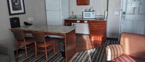 Un espacio habitable compacto con comedor, kitchenette y una puerta que da a otra habitación.