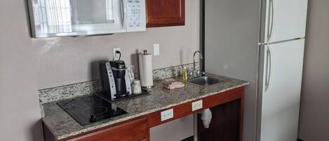 A compact kitchen with a microwave, refrigerator, stove, and sink.
