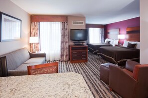 A hotel room with a bed, a sofa, a TV, and a desk.