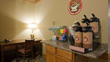 A hotel kitchen with a coffee station, a desk, and a chair.