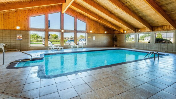 Une piscine intérieure avec un sol carrelé et des poutres en bois.