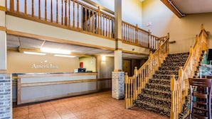 Un hall d’hôtel comprenant un comptoir d’accueil, un escalier et un panneau indiquant la sortie.