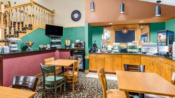 Um restaurante com mesas e cadeiras de madeira, um balcão com uma máquina de café e uma escada com corrimão de madeira.