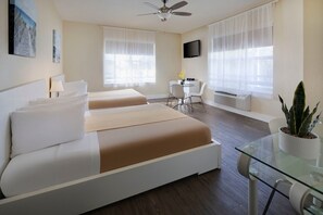 A hotel room with two beds, a desk, a chair, a TV, and a ceiling fan. - Ocean Five Hotel & Studios (Miami Beach)