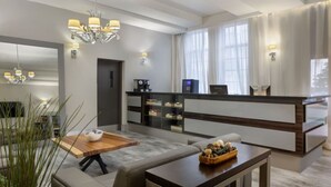 En moderne hotellobby med receptionsdisk, siddeområde og kaffemaskine.