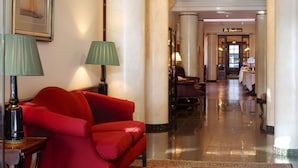 A hotel lobby with a red sofa, a green lamp, and a chandelier. - Eurostars Montgomery (Brussels)