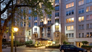 A multi-story hotel with a modern facade, illuminated windows, and a well-lit entrance area. - Eurostars Montgomery (Brussels)