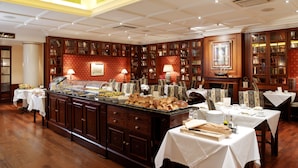 A buffet area with a variety of food items, wooden cabinets, and bookshelves. - Eurostars Montgomery (Brussels)