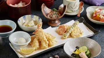Une variété de plats japonais, notamment des beignets de tempura, des sashimis et un bol de soupe miso.
