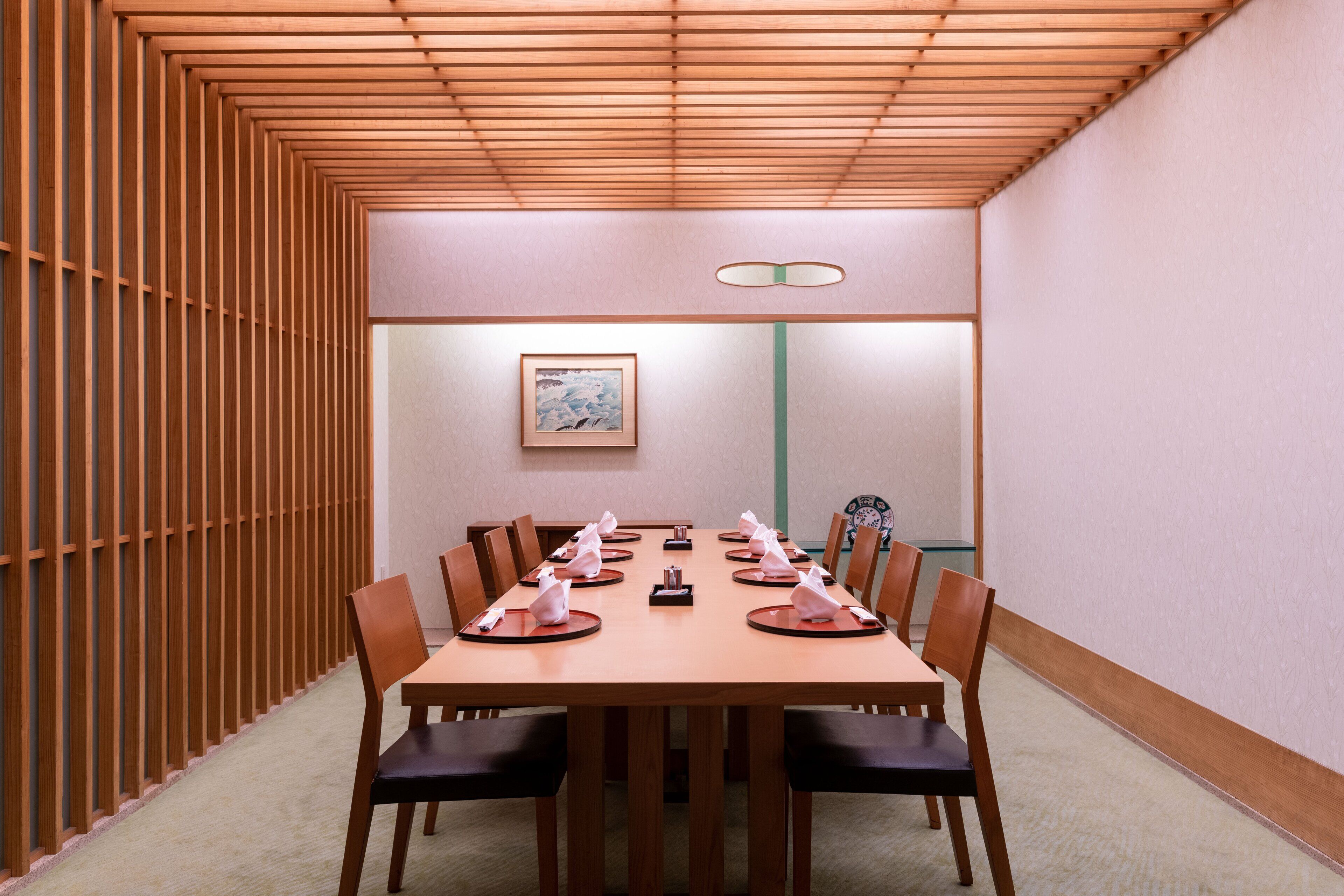 A conference room with a long table, chairs, and a framed picture on the wall.
