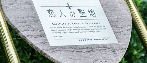 A heart-shaped plaque with text on a metal structure surrounded by greenery.