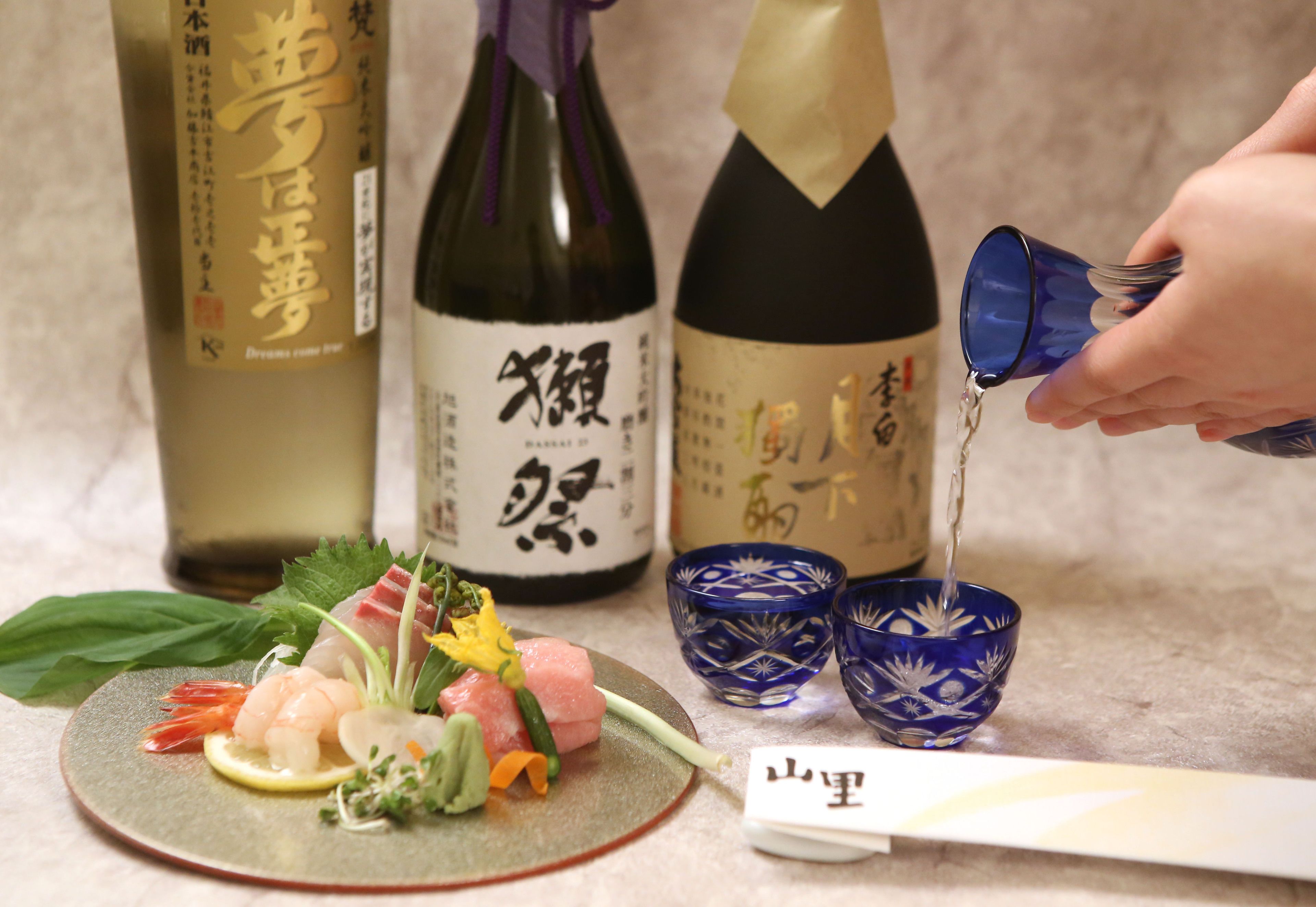 Een sushi gerecht met diverse ingrediënten en een fles sake.