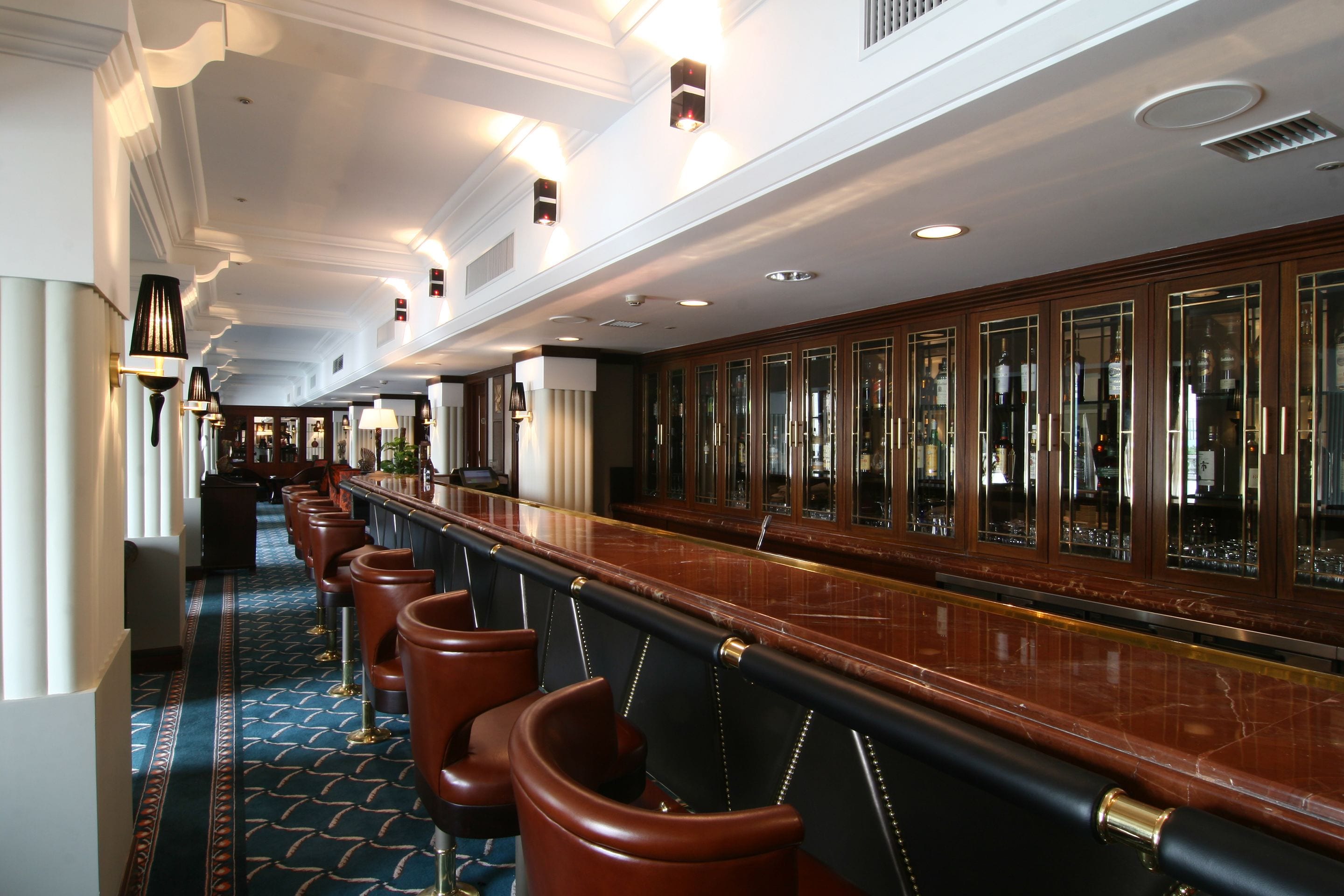 A long bar area with leather barstools and a marble countertop.