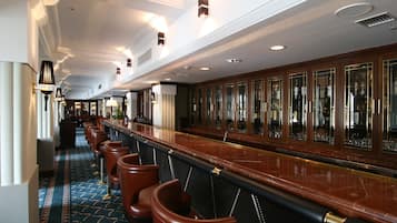 A long bar area with leather barstools and a marble countertop.