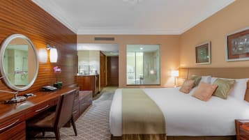 Ein Hotelzimmer mit einem Holztisch, einem großen Bett, einem Spiegel und einem durch eine geöffnete Tür einsehbaren Badezimmer.