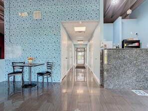 Una hall d'albergo con pavimento lucido, una reception e una zona salotto con sedie e un tavolo.