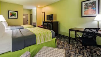 A hotel room with two beds, a desk, a chair, a TV, and a refrigerator.