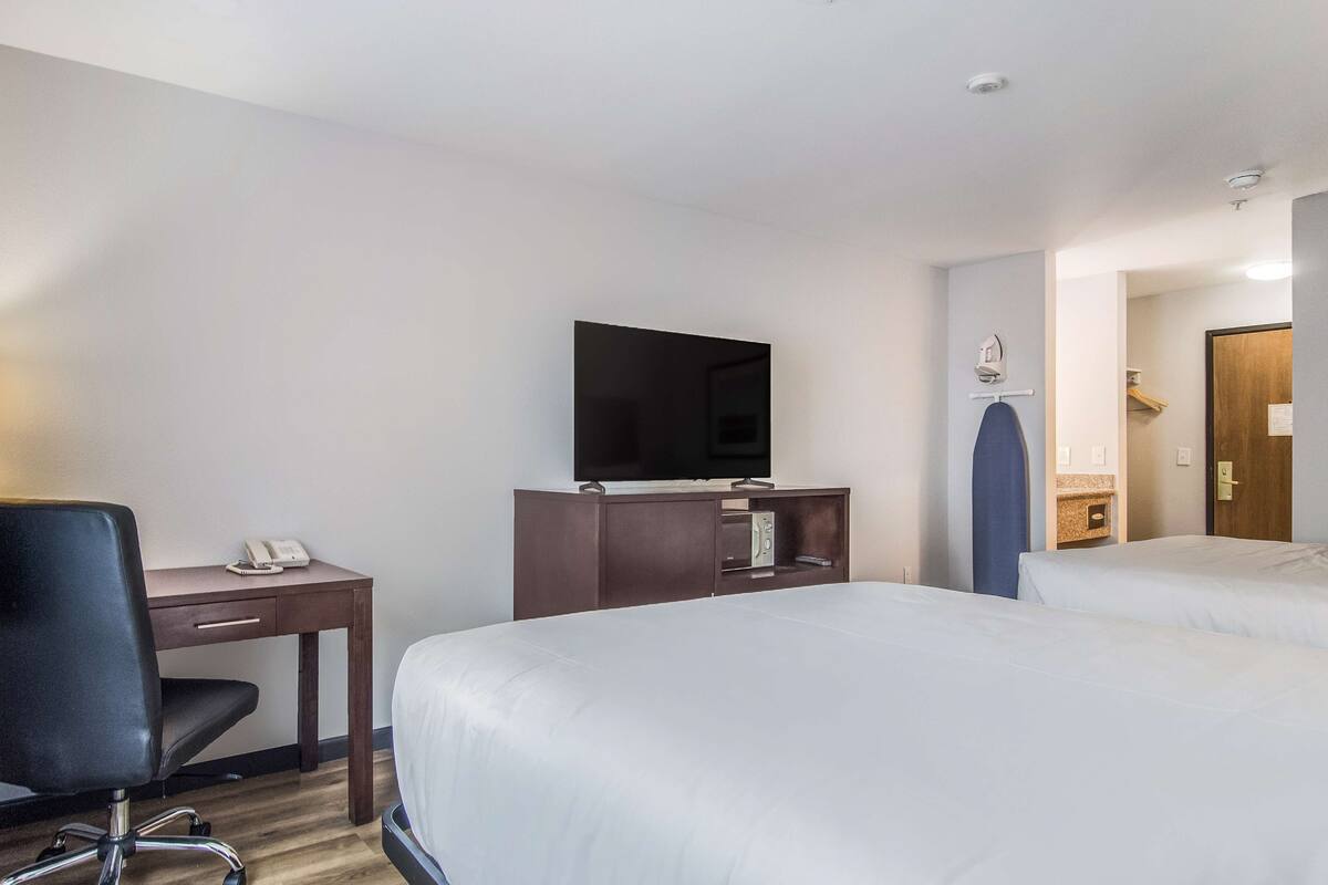 A hotel room with a bed, a desk with a telephone, a television, and a small cabinet.