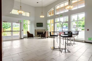 A spacious lobby with large windows, a fireplace, and modern furniture. - Red Lion Inn & Suites Des Moines (Des Moines)