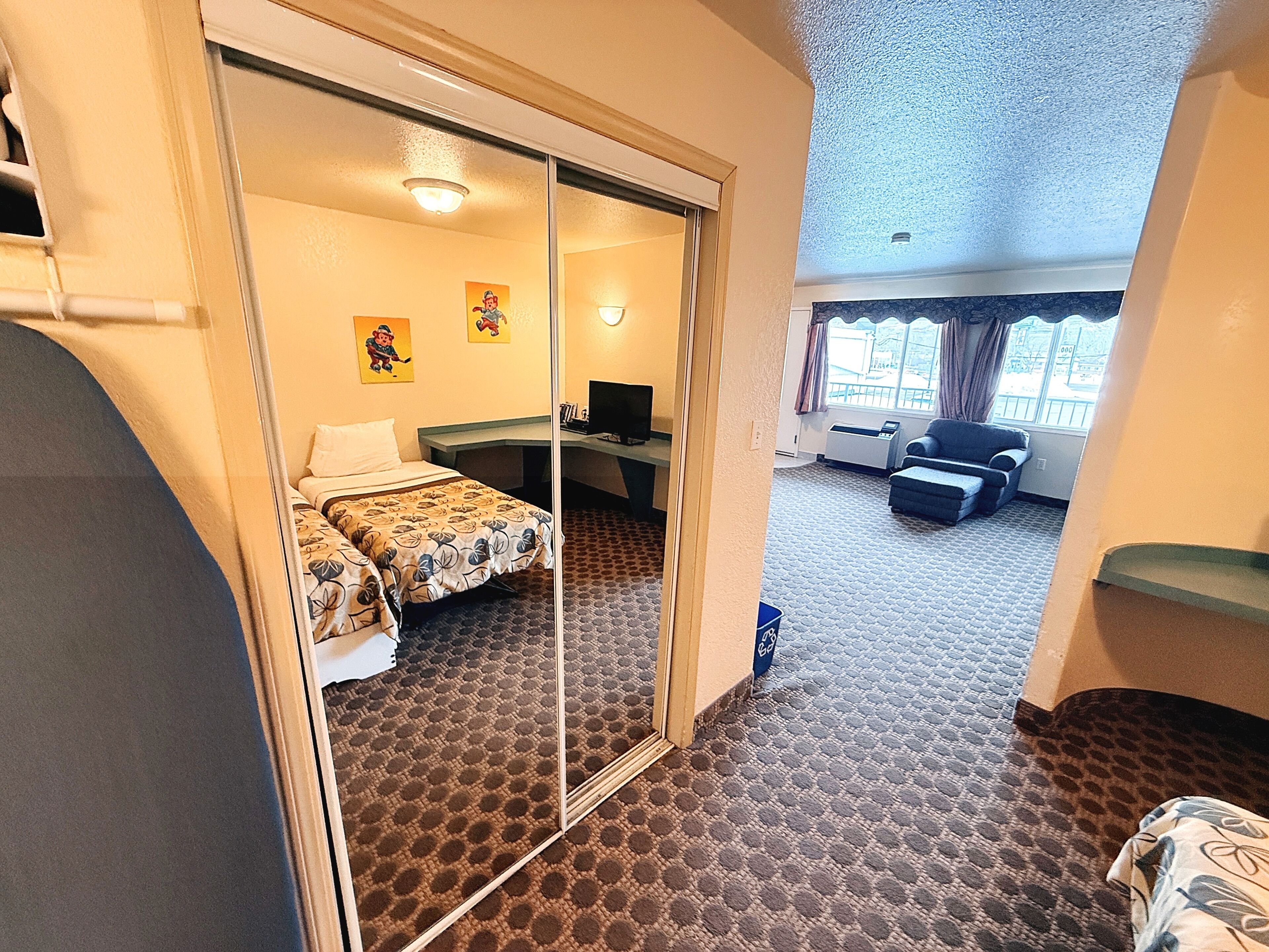 Ein Hotelzimmer mit Bett, Schreibtisch, Stuhl, Fernseher und Blick ins Freie.