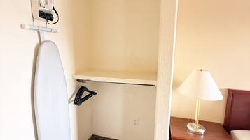 A hotel room with a shower, a small table with a lamp, and a wall-mounted ironing board.