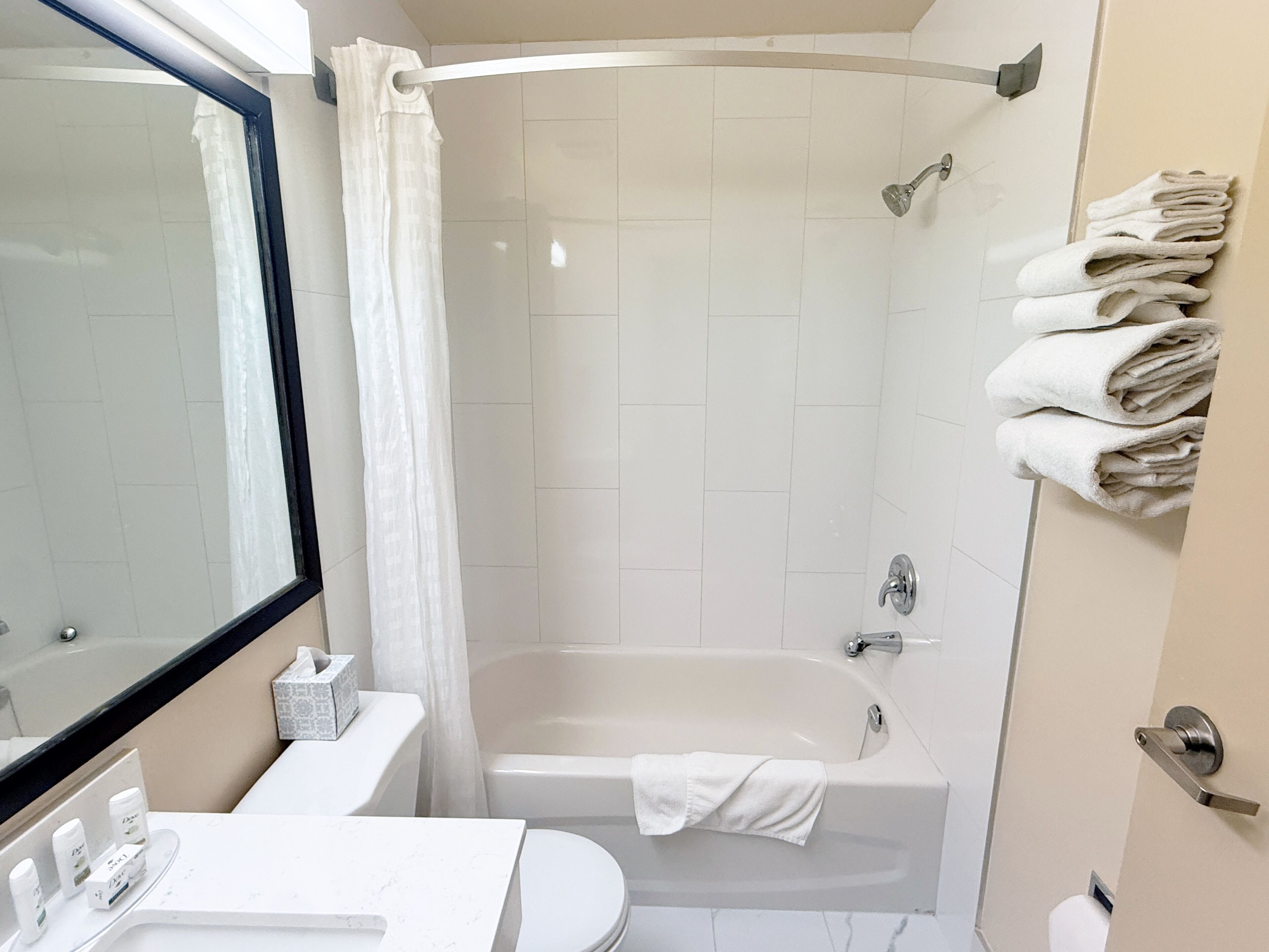 Ein Badezimmer mit einer Badewanne, einer Toilette, einem Waschbecken, einem Spiegel und einem Handtuchhalter.