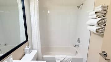 Ein Badezimmer mit einer Badewanne, einer Toilette, einem Waschbecken, einem Spiegel und einem Handtuchhalter.