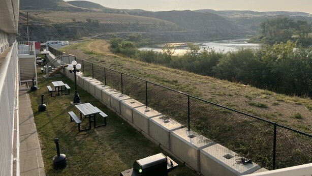 Un balcón con mobiliario exterior, vistas al río y colinas al lejano.